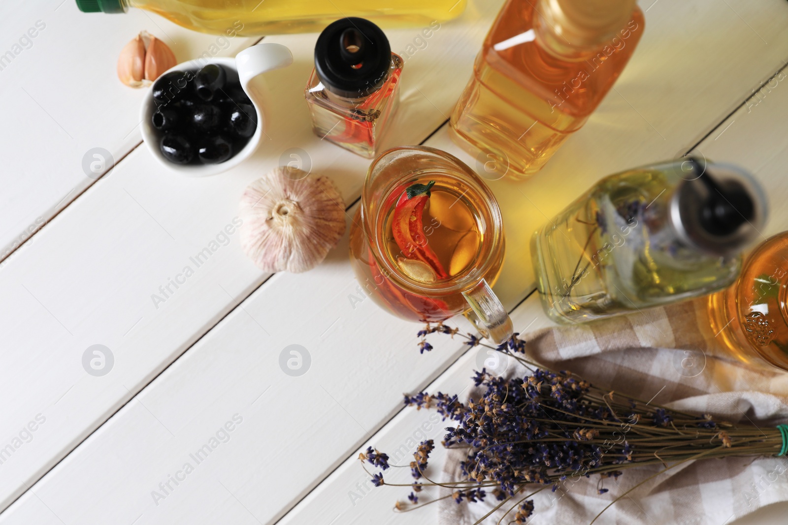 Photo of Different cooking oils and ingredients on white wooden table, above view. Space for text