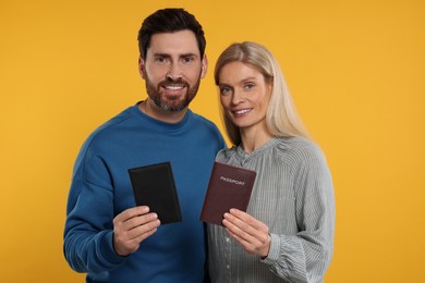 Immigration. Happy man and woman with passports on orange background