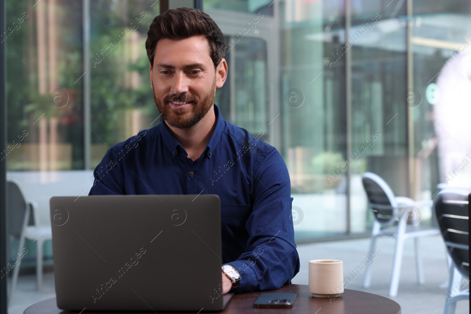 Photo of Man working on laptop at table in cafe