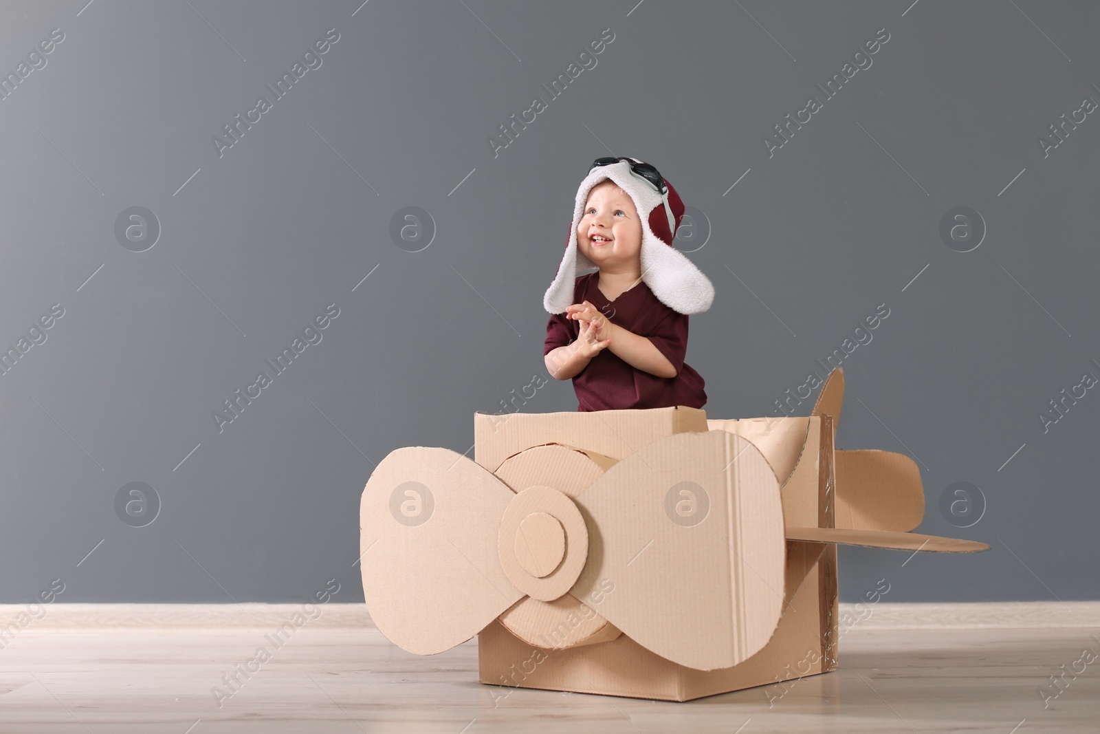 Photo of Adorable little child playing with cardboard plane indoors