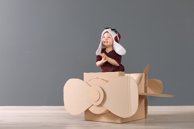 Adorable little child playing with cardboard plane indoors