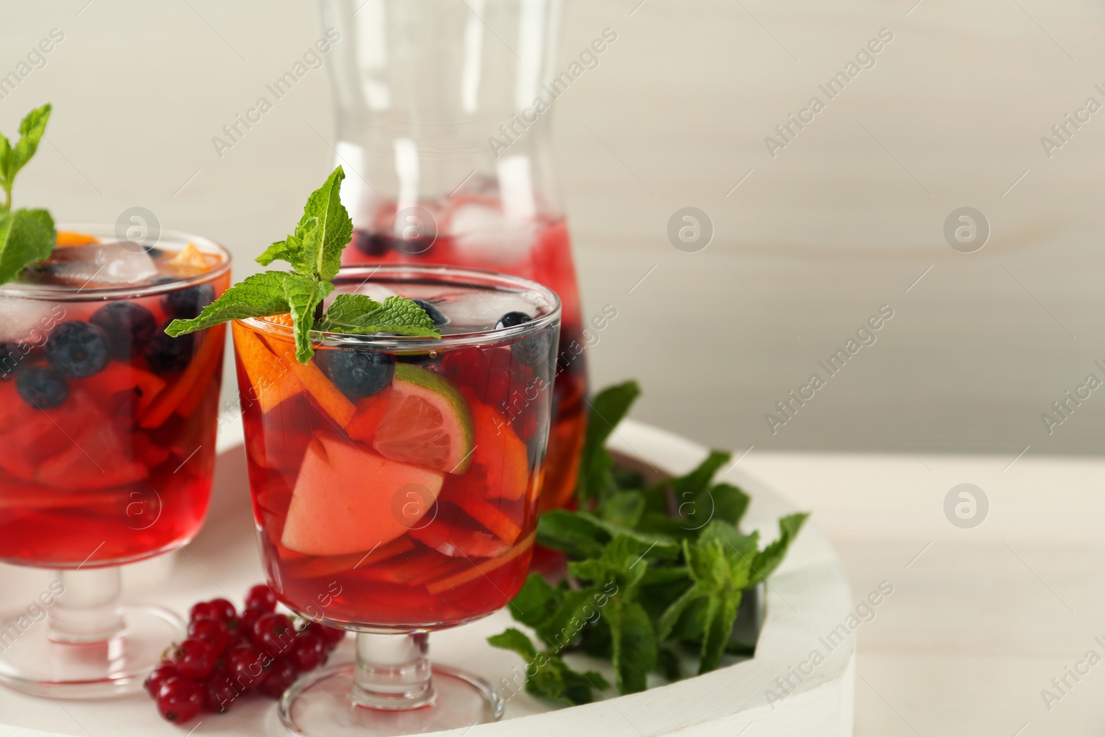 Photo of Delicious Red Sangria and ingredients on white table, space for text