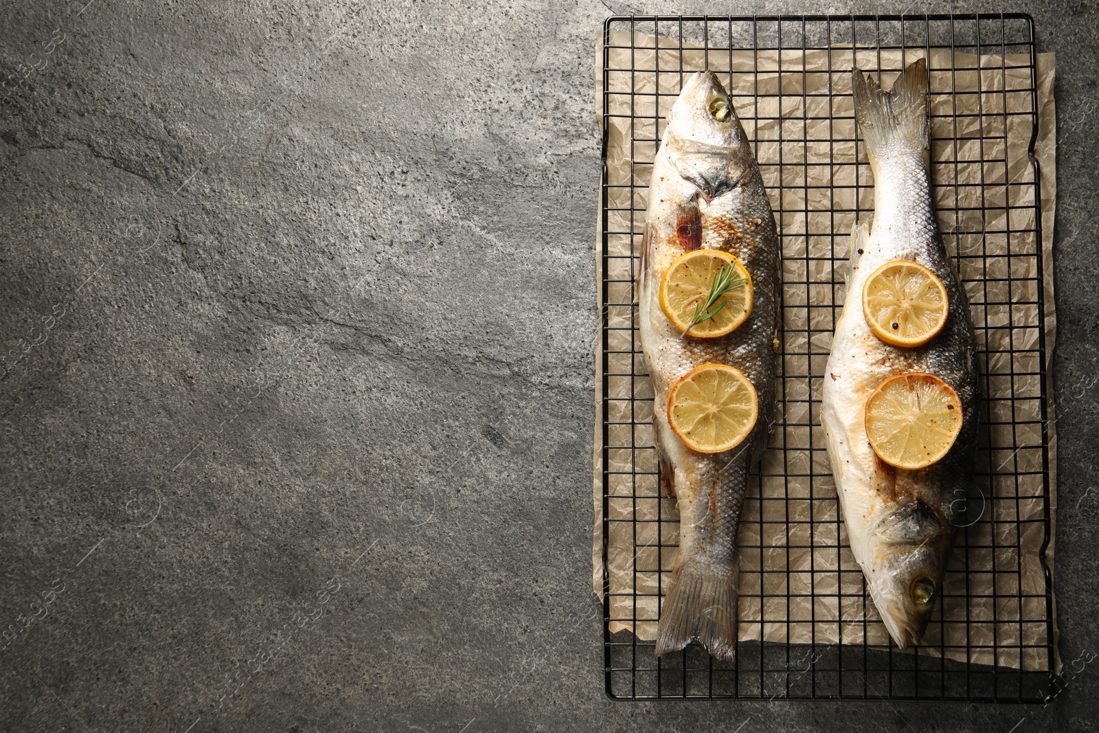 Photo of Baked fish with lemon on grey textured table, top view. Space for text