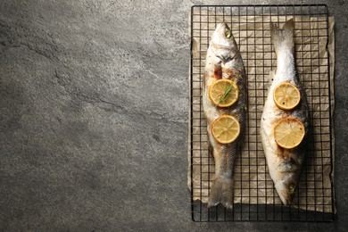 Baked fish with lemon on grey textured table, top view. Space for text