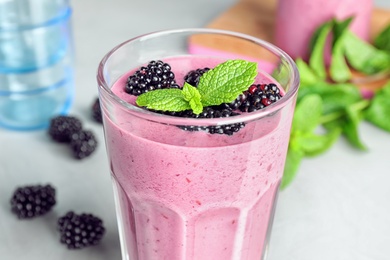 Photo of Glass of blackberry smoothie on table, closeup