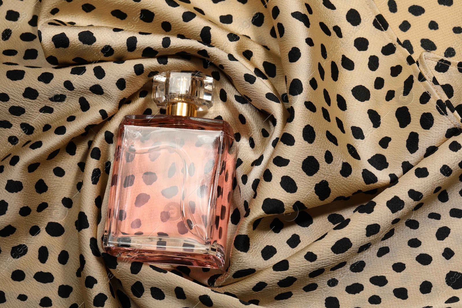 Photo of Luxury perfume in bottle on fabric with leopard pattern, above view