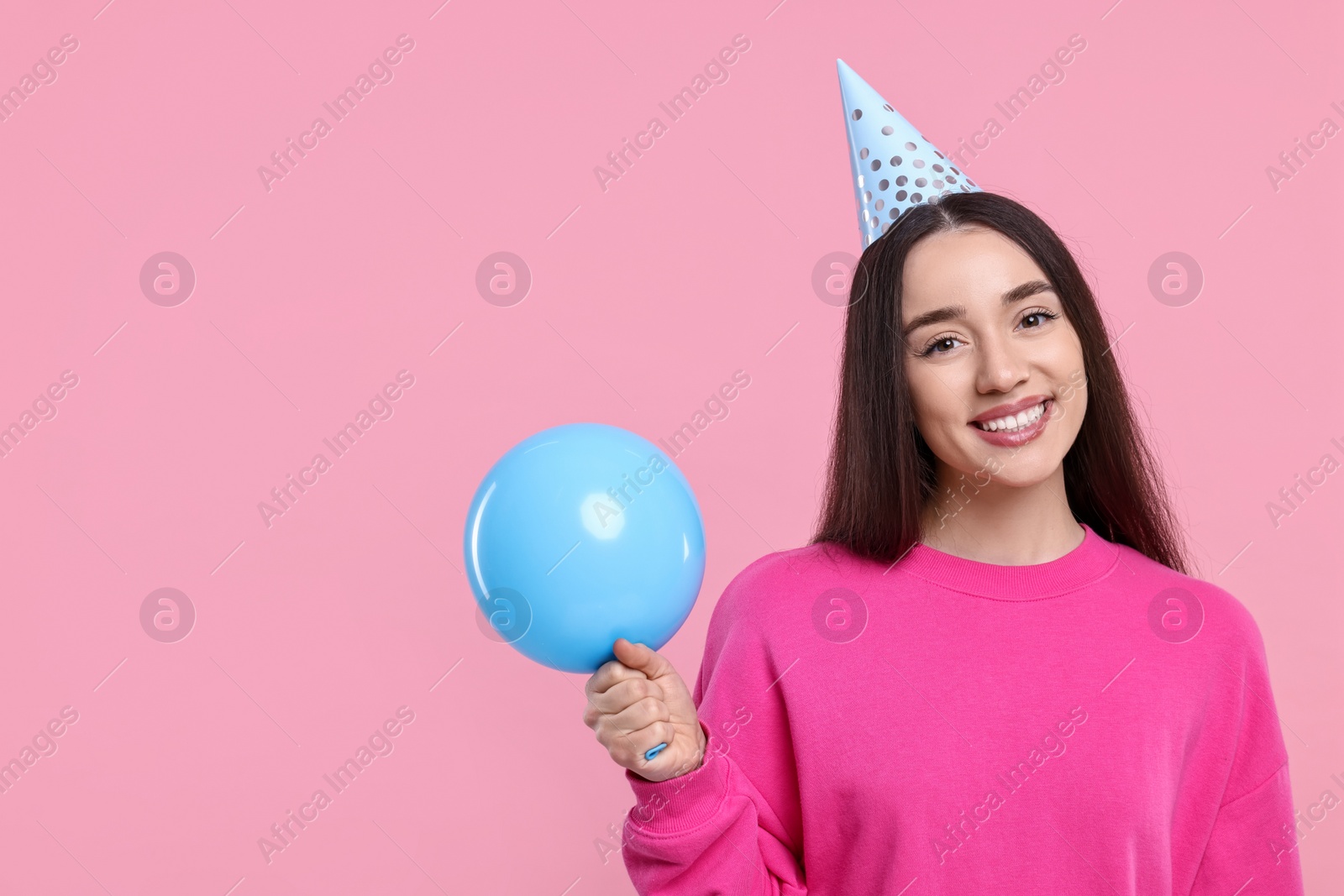 Photo of Happy woman in party hat with balloon on pink background, space for text