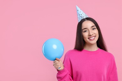 Photo of Happy woman in party hat with balloon on pink background, space for text