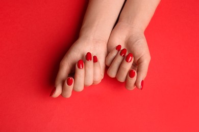 Photo of Woman with gel polish on nails against red background, top view