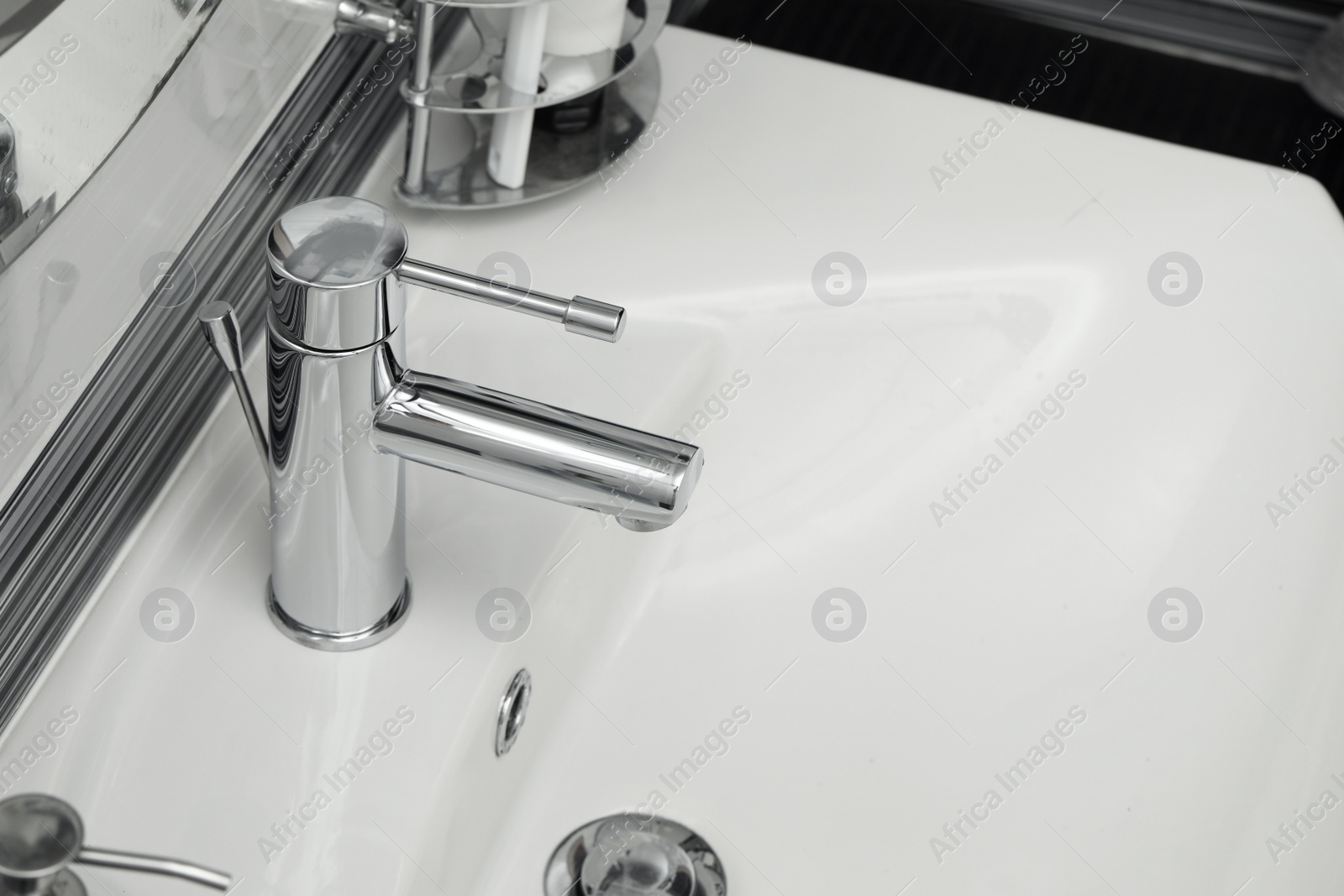 Photo of Clean white sink with shiny water tap in bathroom