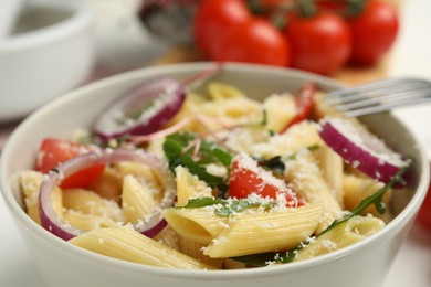 Photo of Bowl of delicious pasta with tomatoes, onion and cheese, closeup