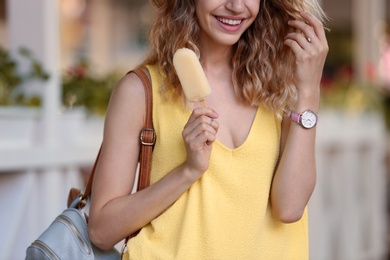 Happy young woman with delicious ice cream outdoors, closeup