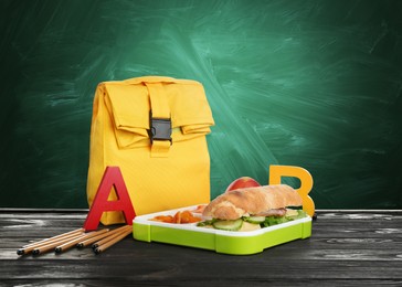 Image of Lunch box with appetizing food and bag on table near green chalkboard