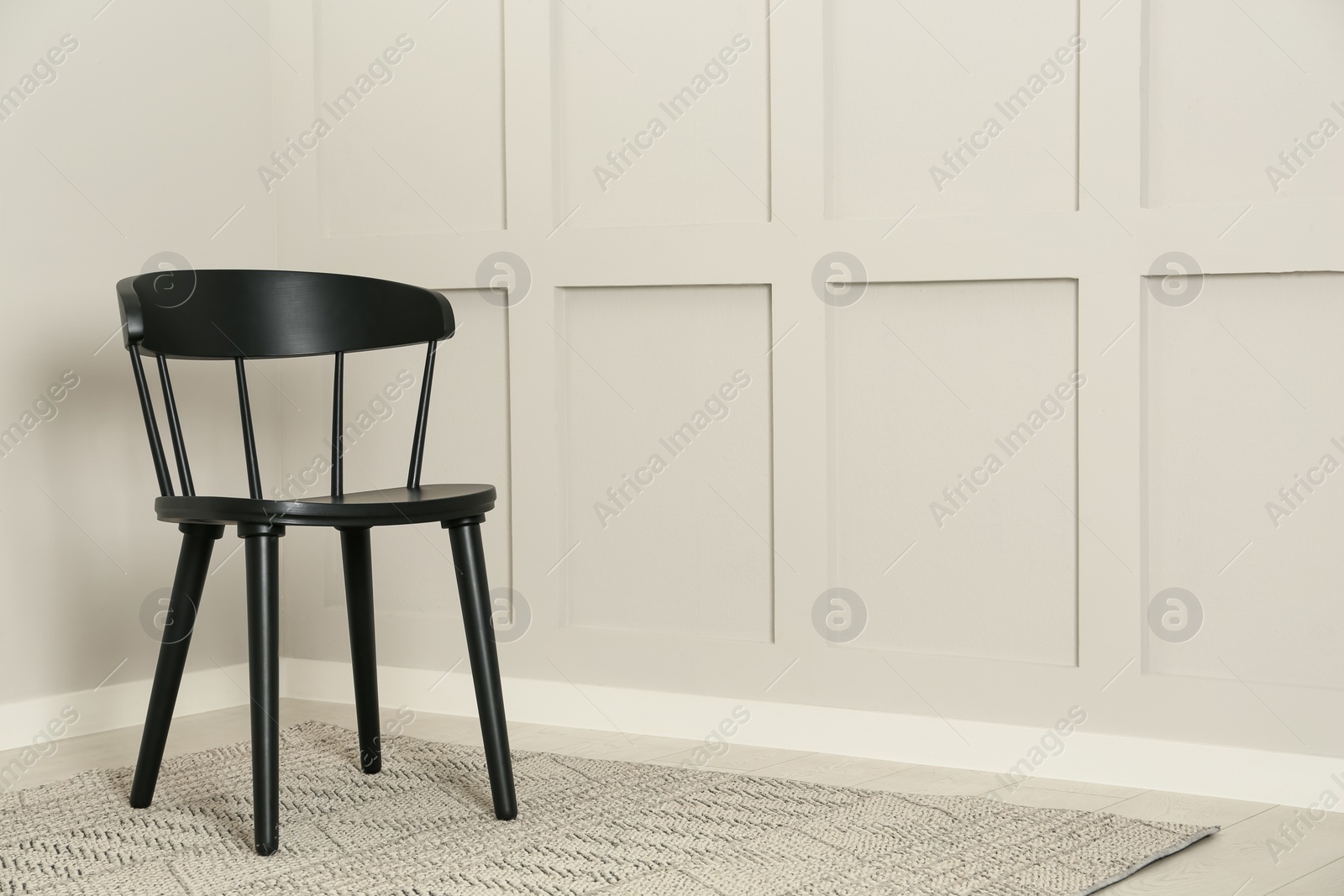 Photo of Black wooden chair near light wall in room. Space for text