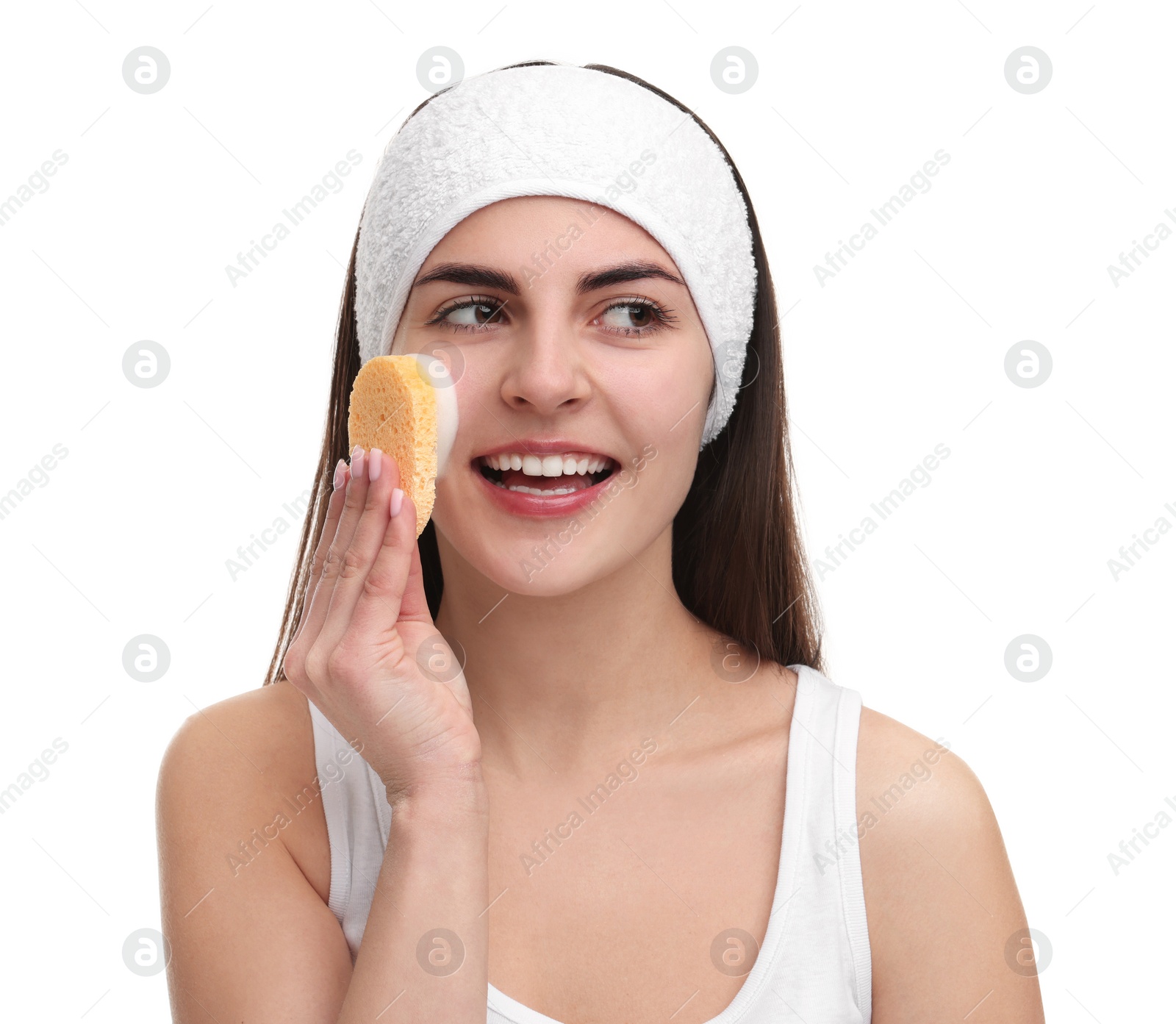 Photo of Young woman with headband washing her face using sponge on white background