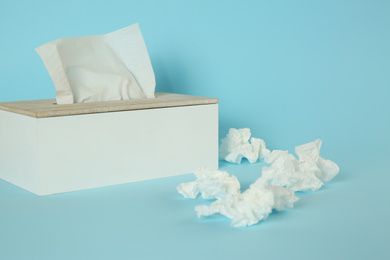 Photo of Used paper tissues and holder on light blue background