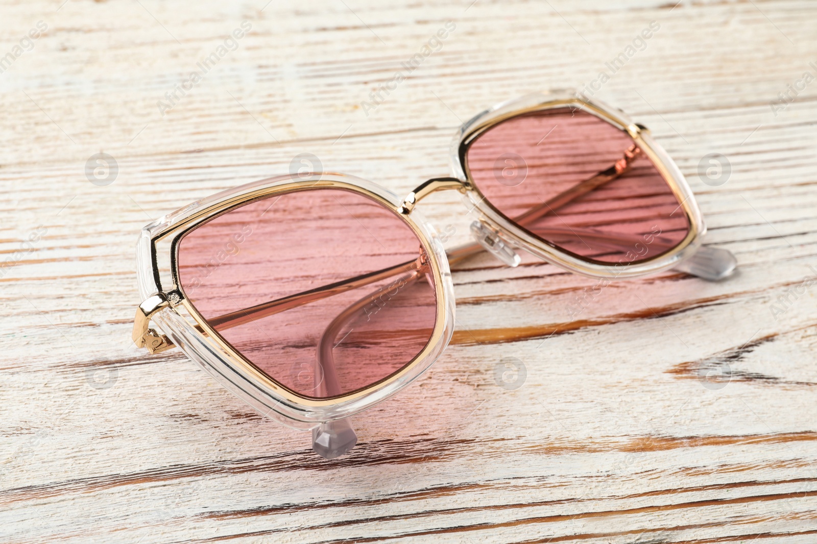 Photo of New stylish sunglasses on white wooden table, closeup