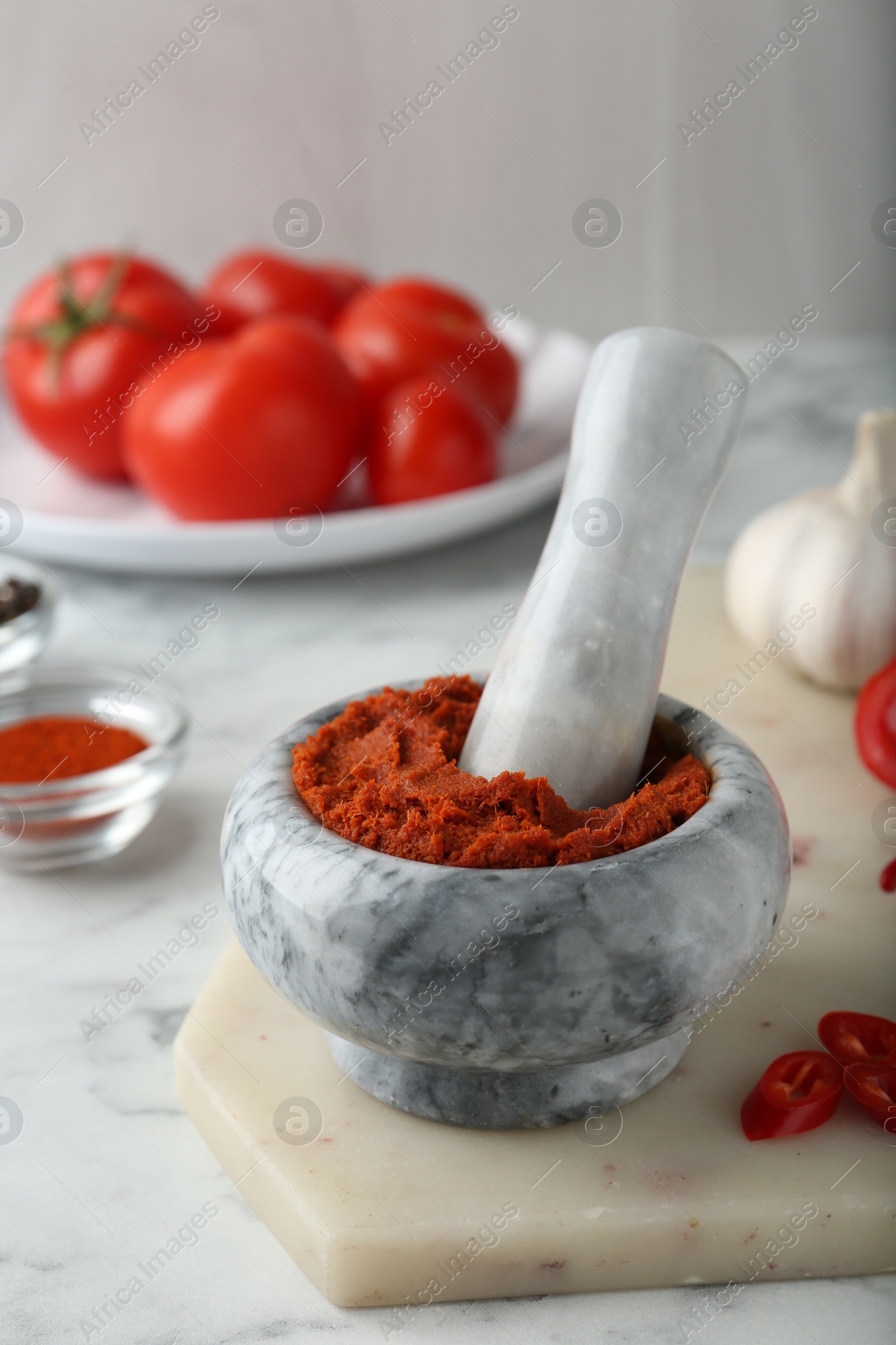 Photo of Red curry paste in mortar on white marble table