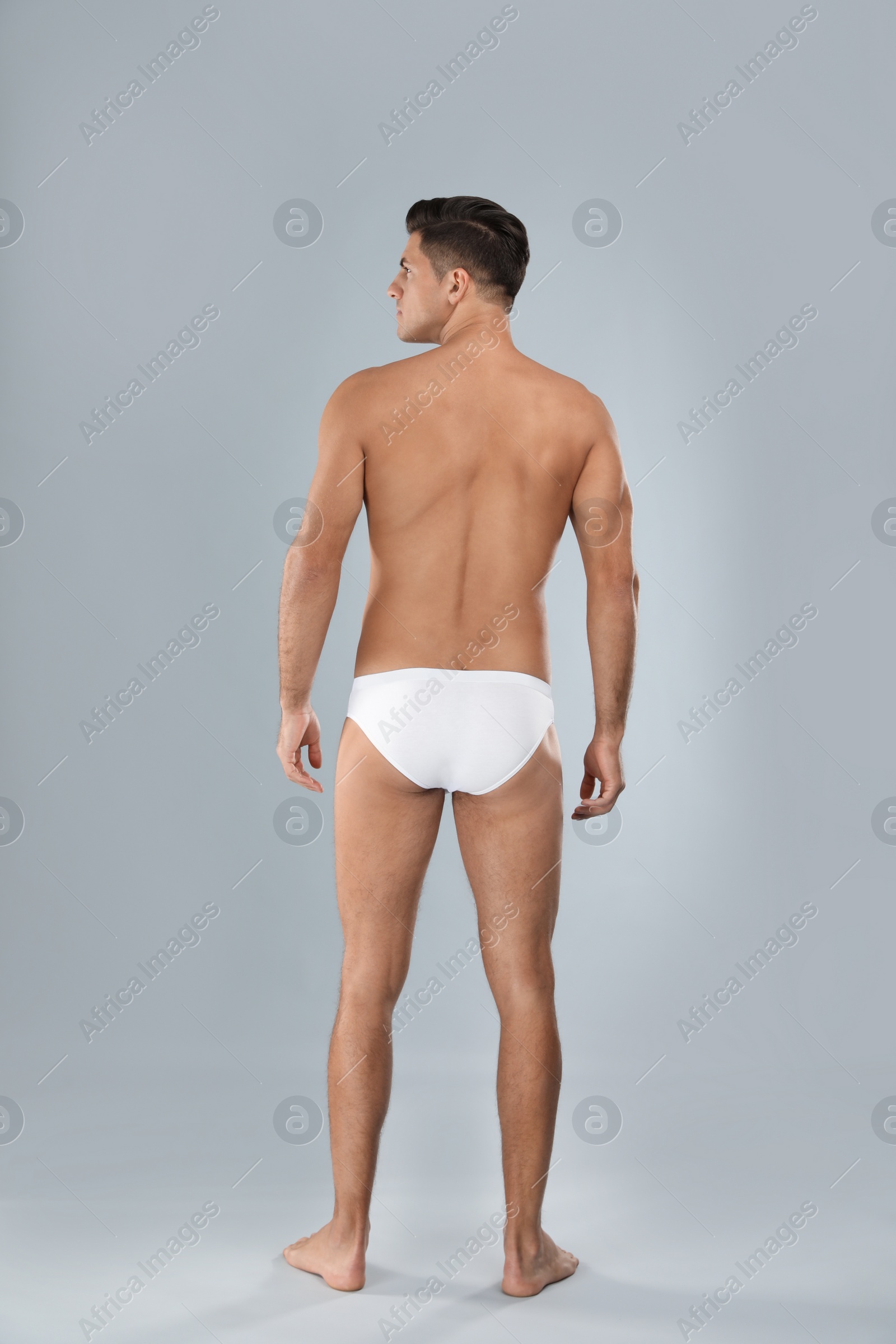 Photo of Handsome man in white underwear on light grey background, back view