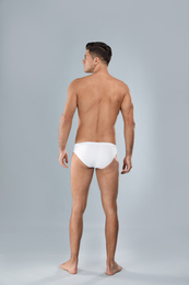 Photo of Handsome man in white underwear on light grey background, back view