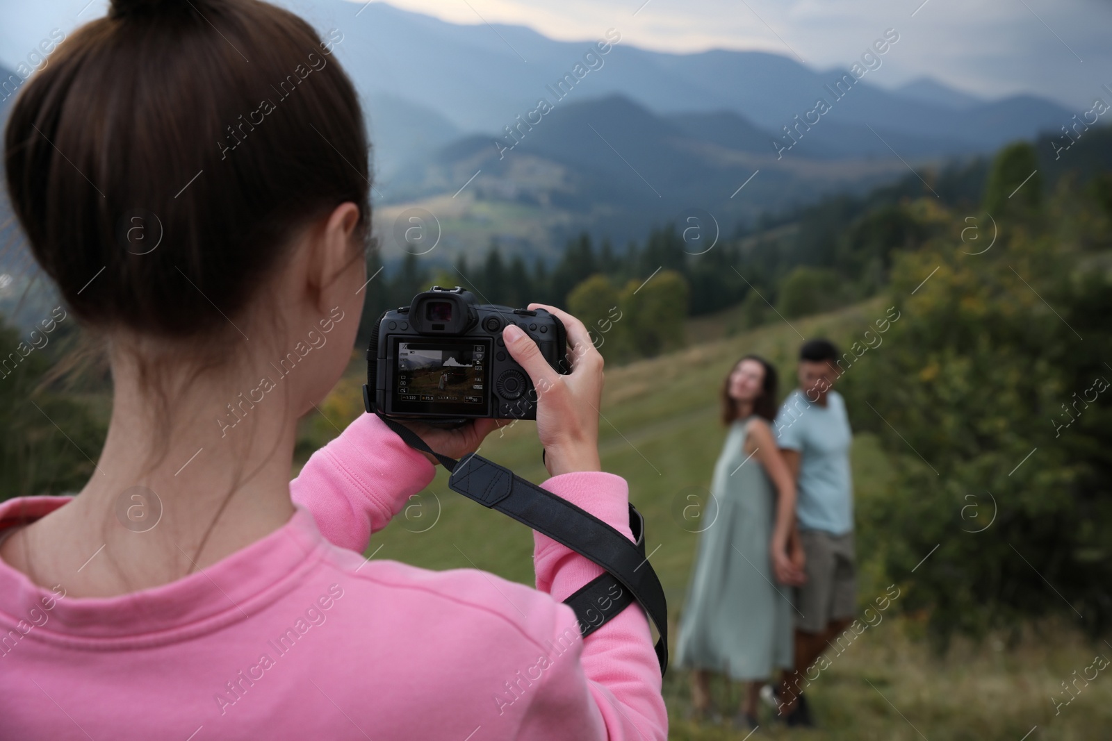 Photo of Professional photographer taking picture of couple in mountains, closeup