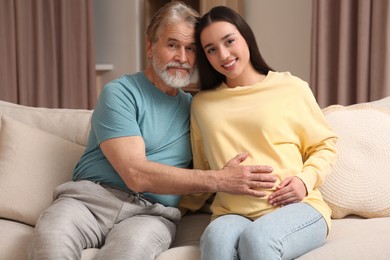 Photo of Father and his pregnant daughter indoors. Grandparents' reaction to future grandson