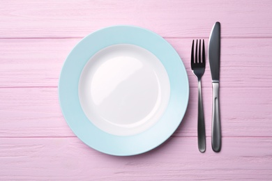 Photo of Stylish ceramic plate and cutlery on wooden background, flat lay