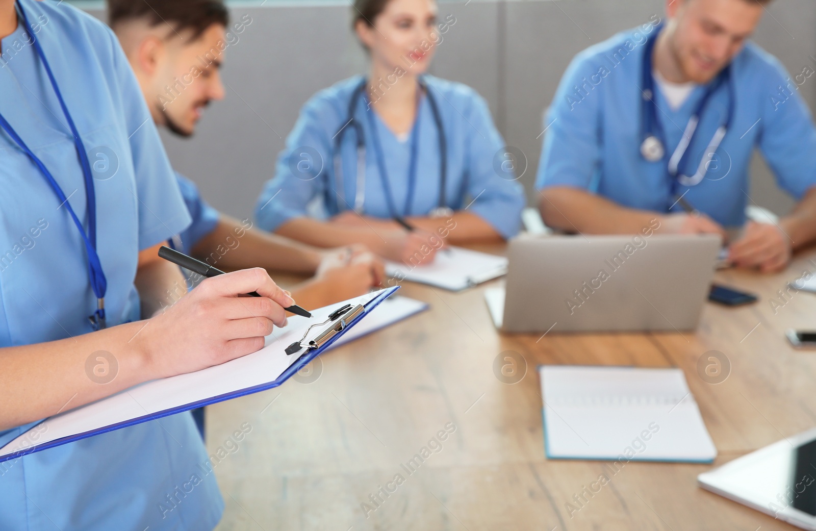 Photo of Medical student with clipboard and her groupmates studying in university library, closeup