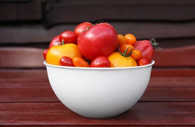 Photo of Bowl with fresh tomatoes on wooden surface, closeup