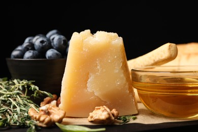 Photo of Delicious parmesan cheese, honey, walnuts and blueberries on table, closeup