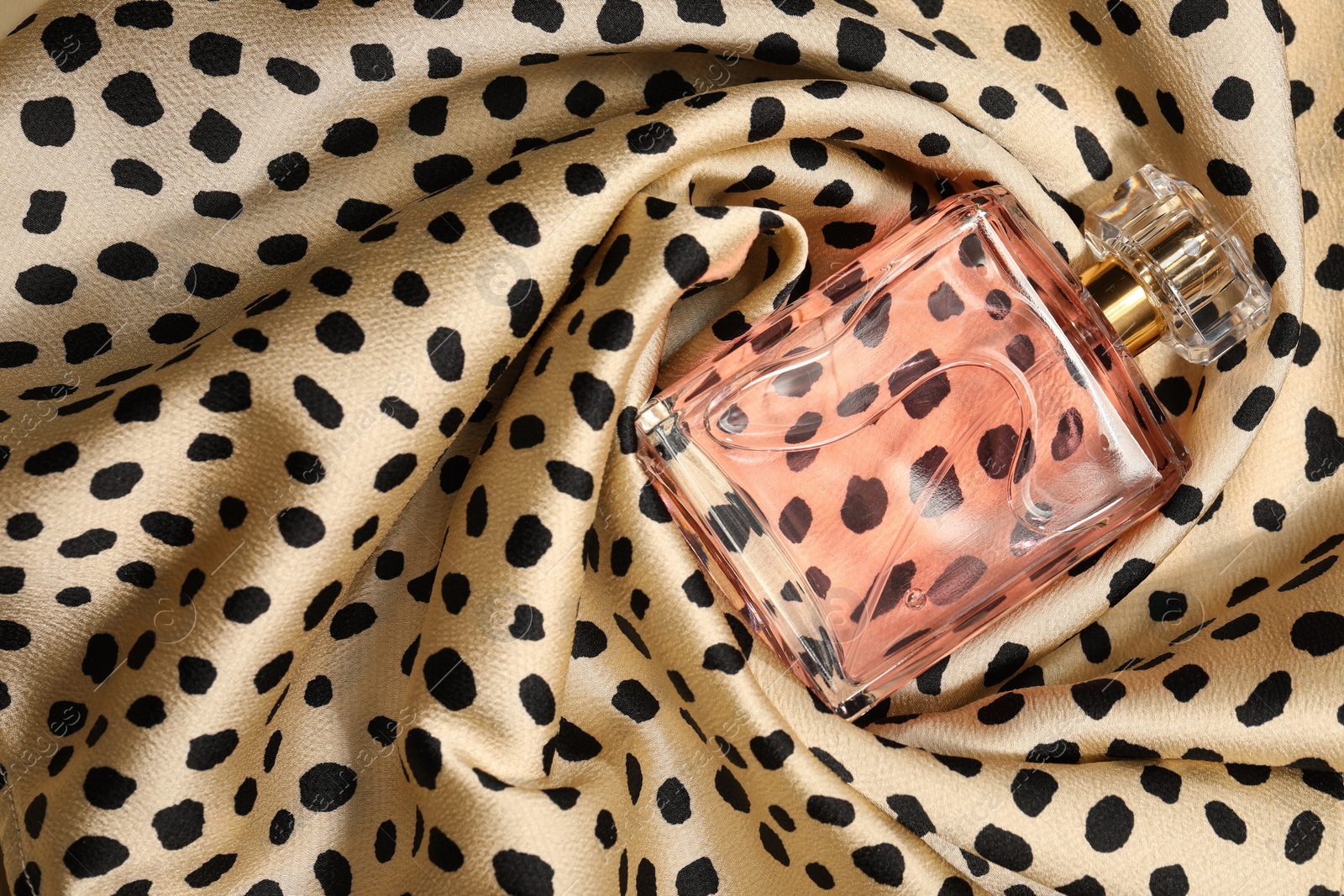 Photo of Luxury perfume in bottle on fabric with leopard pattern, top view