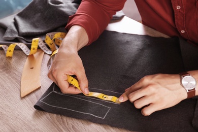 Tailor working with cloth at table in atelier