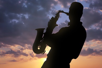 Image of Silhouette of man playing saxophone against beautiful sky at sunset