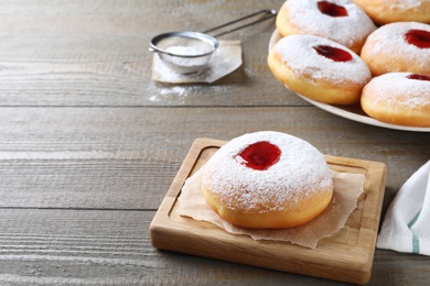 Photo of Hanukkah doughnut with jelly and sugar powder served on wooden table