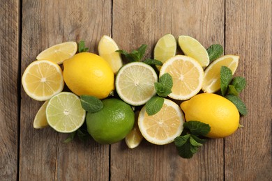 Photo of Fresh ripe lemons, limes and mint leaves on wooden background, flat lay