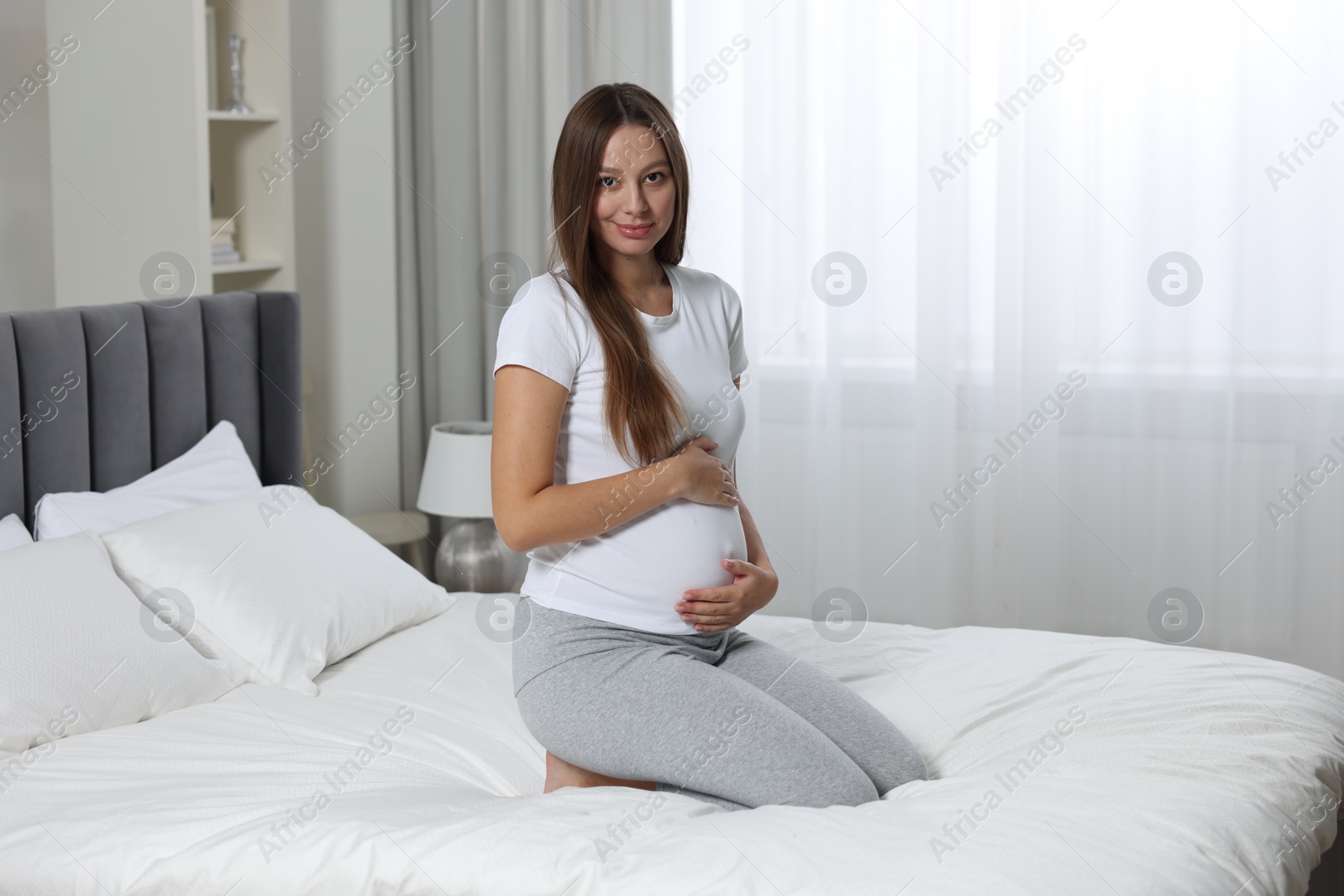 Photo of Beautiful pregnant woman with long hair in bedroom