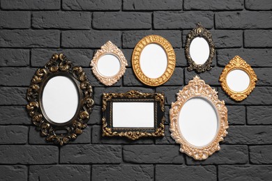 Photo of Empty vintage frames hanging on dark brick wall. Mockup for design