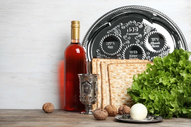 Photo of Symbolic Passover (Pesach) items on table against wooden background, space for text