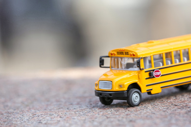 Photo of Yellow toy school bus on road outdoors. Student's transport