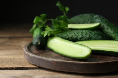 Photo of Fresh ripe cucumbers and parsley on wooden table