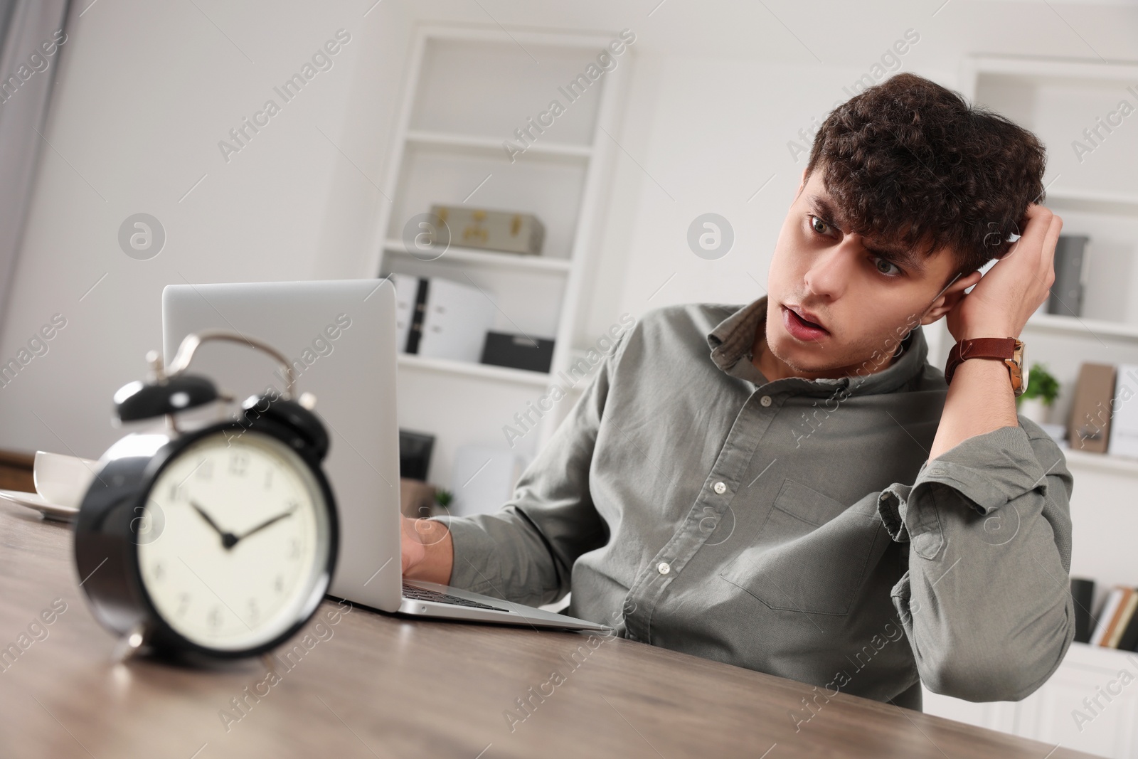 Photo of Emotional young man working at table in office. Deadline concept