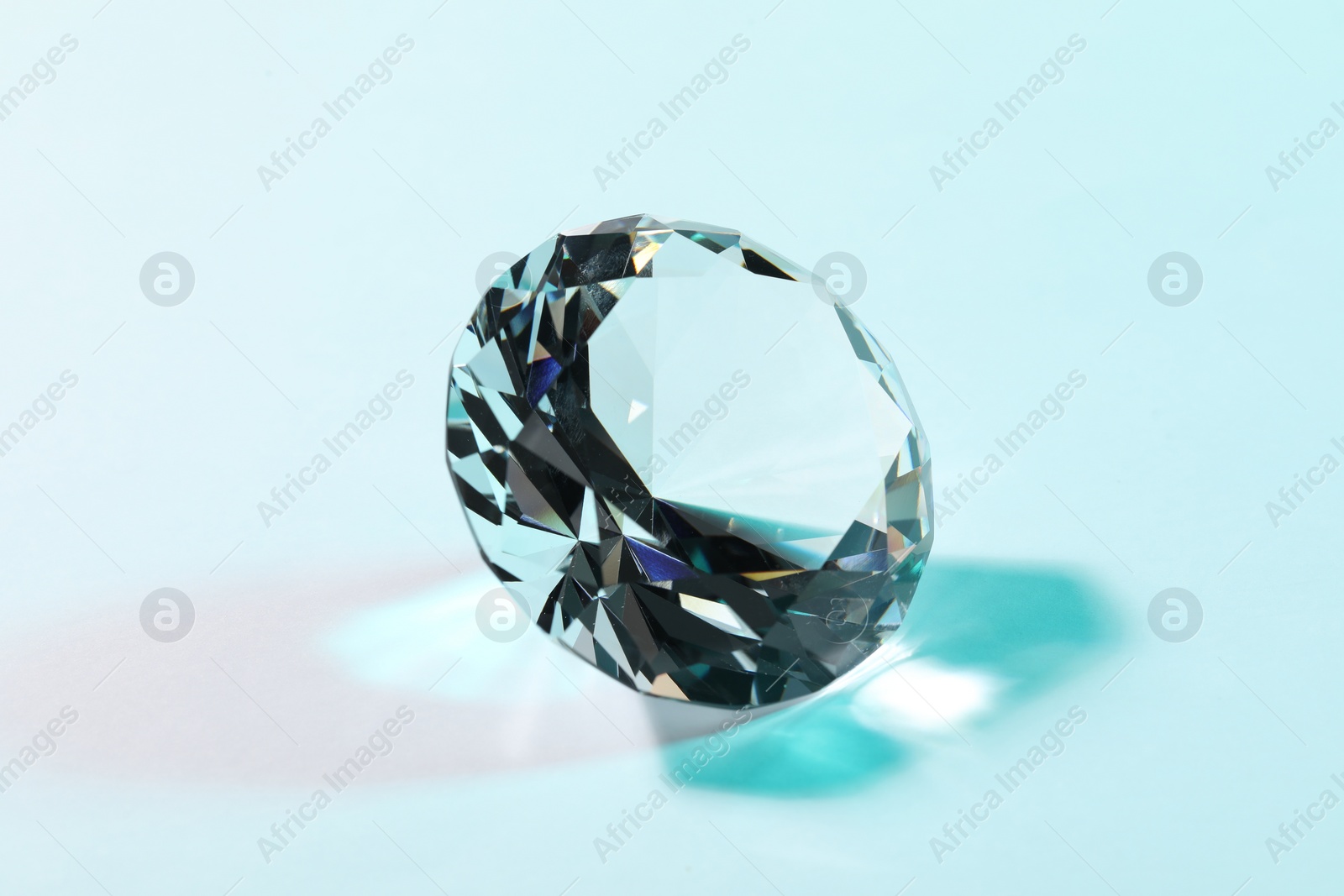 Photo of Beautiful dazzling diamond on turquoise background, closeup