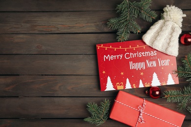 Flat lay composition with greeting card and Christmas decor on wooden background, space for text