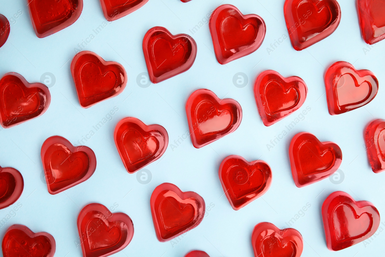 Photo of Sweet heart shaped jelly candies on light blue background, flat lay