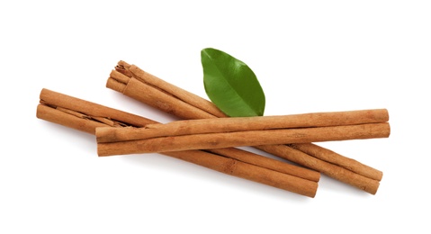 Aromatic dry cinnamon sticks and green leaves on white background, top view