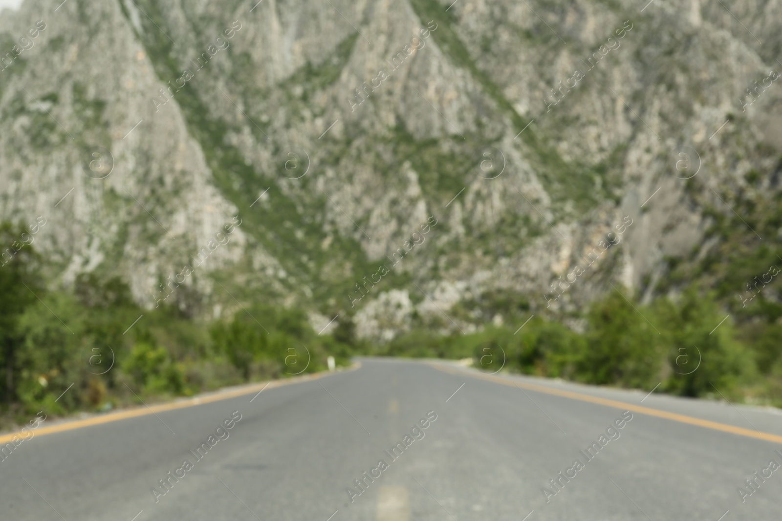 Photo of Big mountains and bushes near road, blurred view