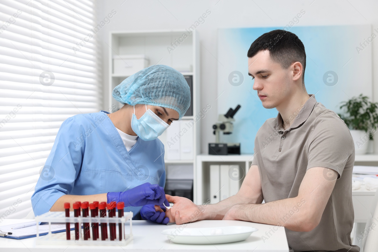 Photo of Laboratory testing. Doctor taking blood sample from patient at white table in hospital