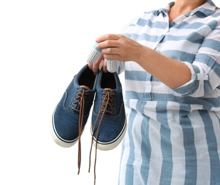 Photo of Woman putting capsule shoe freshener in footwear on white background, closeup