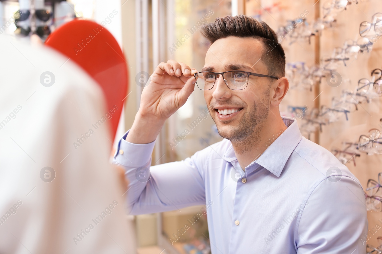 Photo of Man trying on glasses in optical store. Ophthalmologist prescription