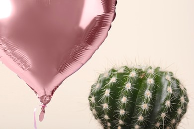 Pink balloon near cacti on beige background